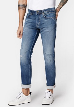 Niebieskie dżinsy o wąskim kroju, z przetarciami i podwiniętymi mankietami. Posiadają klasyczne kieszenie oraz zamek błyskawiczny z zapięciem na guzik.