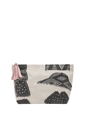 Beżowy materiałowy woreczek z czarnymi geometrycznymi wzorami naszywek, srebrnymi ćwiekami oraz różowym skórzanym chwostem przymocowanym do zamka.