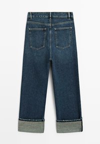 Dżinsy w ciemnoniebieskim kolorze, z krótkim fasonem i podwiniętymi mankietami. Akcenty na tylnej kieszeni mają kształt kwadratu z widocznym przeszyciem.