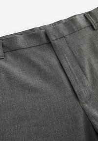 Graue maßgeschneiderte Hose aus einem glatten Stoff mit flacher Vorderseite, sichtbarem Bund und klaren Linien, ausgestattet mit schrägen Seitentaschen.