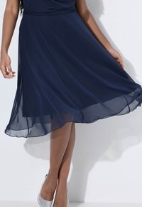 Marineblaues Chiffonkleid mit einer fließenden A-Linie, das ein gerafftes Oberteil und einen Saum aufweist, der sanft am Knie fällt.