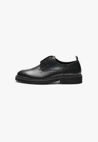 Zapato de cuero negro con un acabado suave, punta redonda, paneles laterales elásticos y una suela de goma estriada. Diseño minimalista con costuras sutiles.