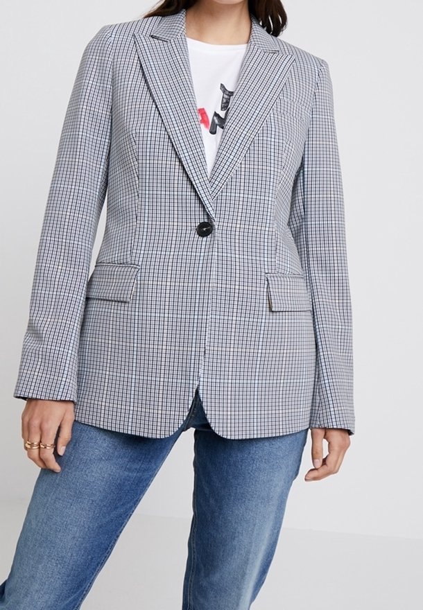 Blazer grigio e bianco a quadri con texture, colletto a notched, chiusura a un bottone e due tasche frontali, abbinato a una maglietta bianca basic.