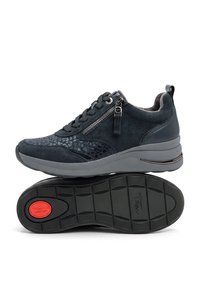 Zapatilla deportiva azul oscuro con cordones en la parte delantera, cremallera lateral, parte superior con estampado, suela gruesa gris y logo circular rojo "Tamaris Comfort" en la suela negra.