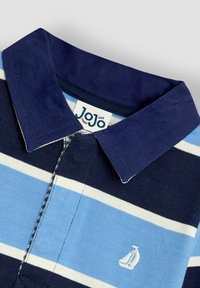 Raidoitu polo-paita tummansinisessä, sinisessä ja valkoisessa. Varustettu kauluksella, nappilista ja brodeeratulla purjevene-logolla. Valmistettu pehmeästä puuvillamateriaalista.