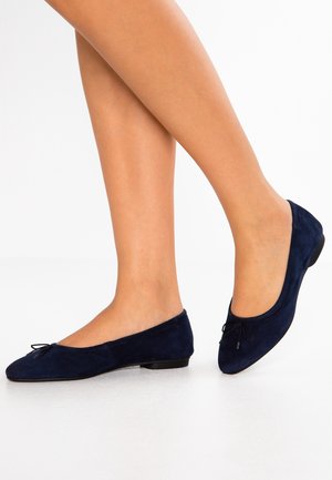 Granatowe baleriny z zamszu z zaokrąglonym noskiem, płaskim obcasem i ozdobną kokardką z przodu. Gładka faktura z subtelnym połyskiem.