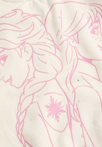 Wit sweatshirt met roze lijntekeningen van twee figuren en een sneeuwvlokontwerp. Ingebedde rhinestones voegen subtiele textuur toe. Zacht stof.