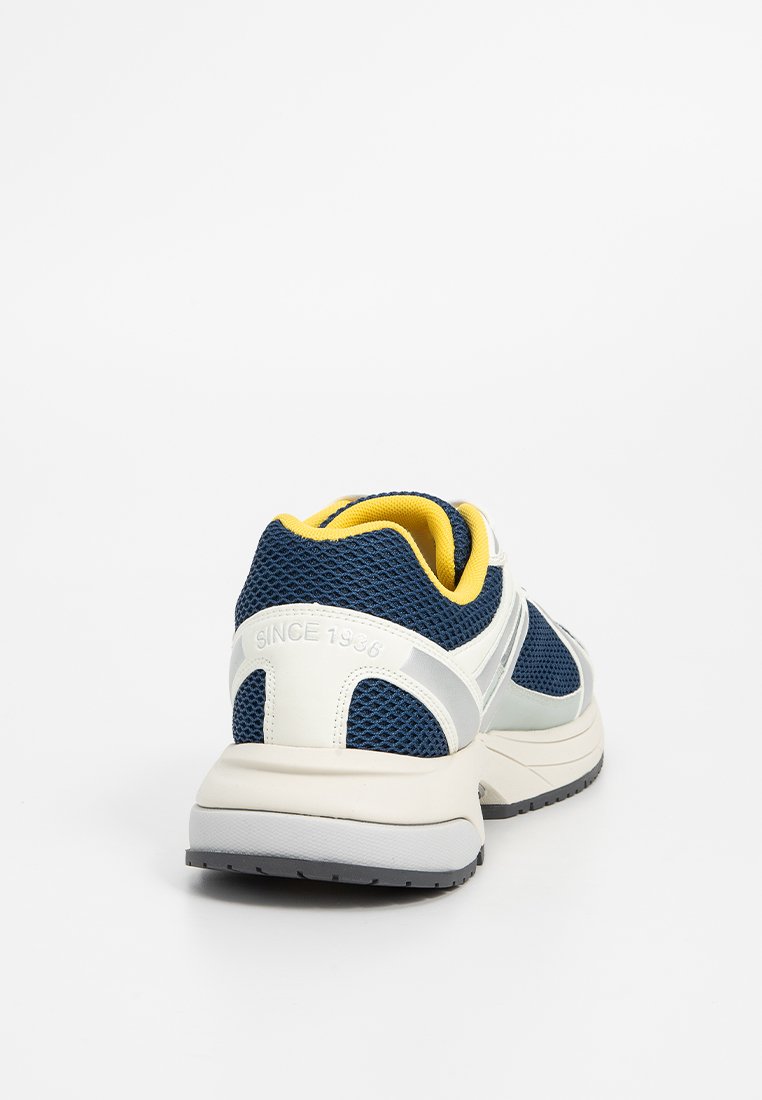 Scarpa da ginnastica a rete blu con accenti gialli e tallone bianco. Caratterizzata da una suola imbottita e un dettaglio "SINCE 1936" sul retro.