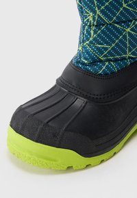 Botín negro impermeable con una suela verde texturizada y un upper azul que presenta un patrón geométrico de líneas verdes y puntos azules.