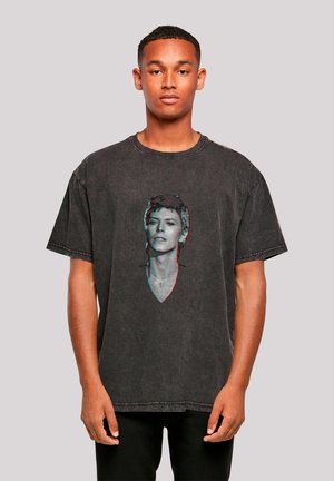 Black oversized t-shirt in a faded, textured fabric with a front graphic of a person’s face in 3D effect, featuring a V-neck design.