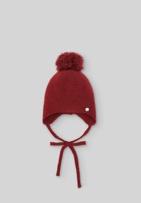 Cappello di lana rosso con pompon sulla cima, orecchiette e lacci. Presenta un accento argentato sul lato. Texture morbida e forma arrotondata.