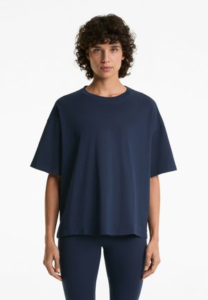 Mørkeblå oversized t-shirt med korte ærmer, rund halsudskæring og let tekstur, parret med matchende tætsiddende leggings.