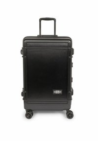 Valigia rigida nera con texture spazzolata verticale, manico retrattile, quattro ruote e dettaglio del logo sulla parte anteriore.