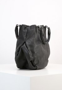 Czarna, miękka skórzana torebka z krótkimi podwójnymi uchwytami, zgromadzonym na górze, umieszczona na białym piedestale na jednolitym tle.