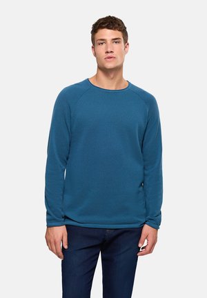 Suéter azul texturizado de manga larga con cuello redondo y puños acanalados, combinado con jeans oscuros de mezclilla.