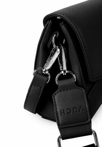 Černá kožená kabelka se stříbrnými detaily, se zapínáním na zip a nastavitelným popruhem. Texturovaný povrch a logo na popruhu.