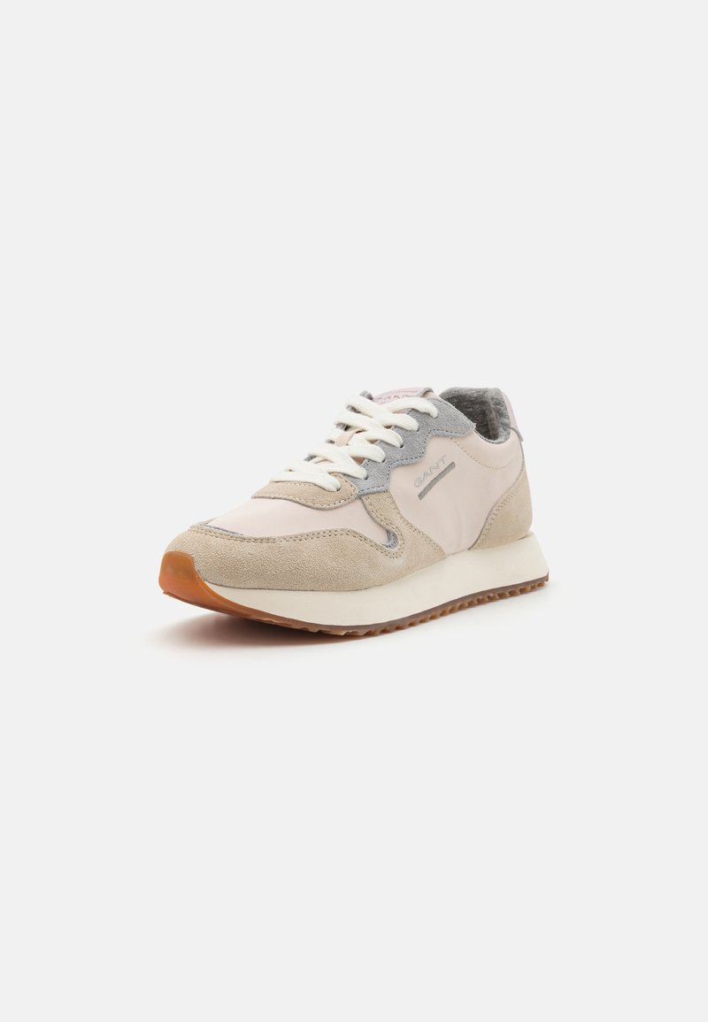Leichte Sneaker in Beige und Grau, mit einem Obermaterial aus Wildleder, strukturierten Akzenten, weißen Schnürsenkeln und einer Gummisohle.