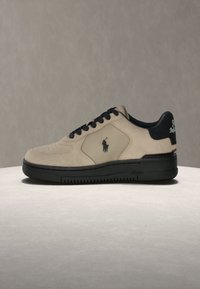 Μπεζ και μαύρο sneaker χαμηλού τύπου με μαύρα κορδόνια, μαύρη σόλα και λογότυπο παίκτη πόλο στην πλευρά και στην πίσω ετικέτα.