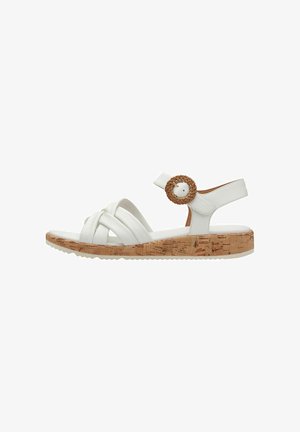 White sandal with cross-strap design, cork-textured sole, and an adjustable ankle strap featuring a woven circle accent.