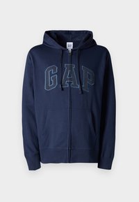 Sudadera marinera con cremallera en el frente y gran logo de "GAP" en azul claro. Hecha de material suave de algodón, cuenta con capucha y bolsillos frontales.