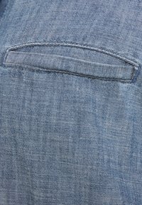 Poche en tissu en denim de couleur bleu clair, présentant une coupe droite et une texture subtile. Les bords sont cousus et il n'y a ni ornements ni motifs.