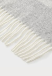 Grå uldhalstørklæde med en blød tekstur, der har hvidt frynse langs den nederste kant. Designet viser en gradient skyggeeffekt.