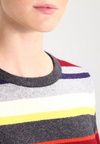 Gestreifter Pullover mit mehreren Farben, darunter Grau, Rot, Gelb und Lila. Runder Halsausschnitt mit einer weichen Textur.