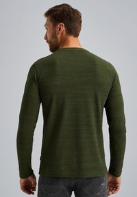 Langärmliges grünes Hemd aus strukturiertem Stoff mit Rundhalsausschnitt, das ein geripptes Design und eine taillierte Silhouette aufweist.