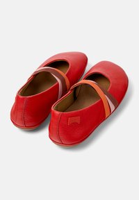 Ballerine in pelle rossa con punta arrotondata, dotate di fasce elastiche nei toni di rosa, marrone e arancione sulla parte superiore. Logo Camper sul tallone.