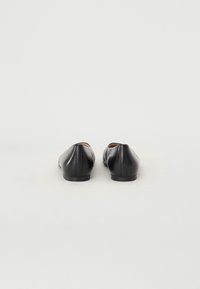 Ballerines en cuir noir avec un bout rond, texture lisse et un talon bas et plat, mettant en valeur des lignes épurées et un design sobre.