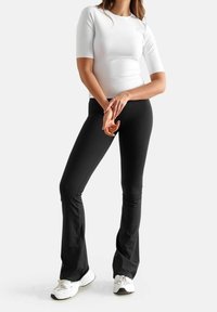 Pantaloni neri a palazzo abbinati a una maglietta fitted bianca a maniche corte, entrambi realizzati in tessuto morbido, con un design pulito e una vestibilità casual.
