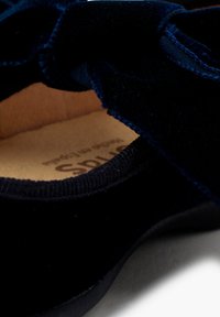 Boty z navy modrého sametu s jemnou texturou, zdobené mašlí na svršku a hladkou, flexibilní podrážkou. Vnitřek je podšitý béžovou látkou.