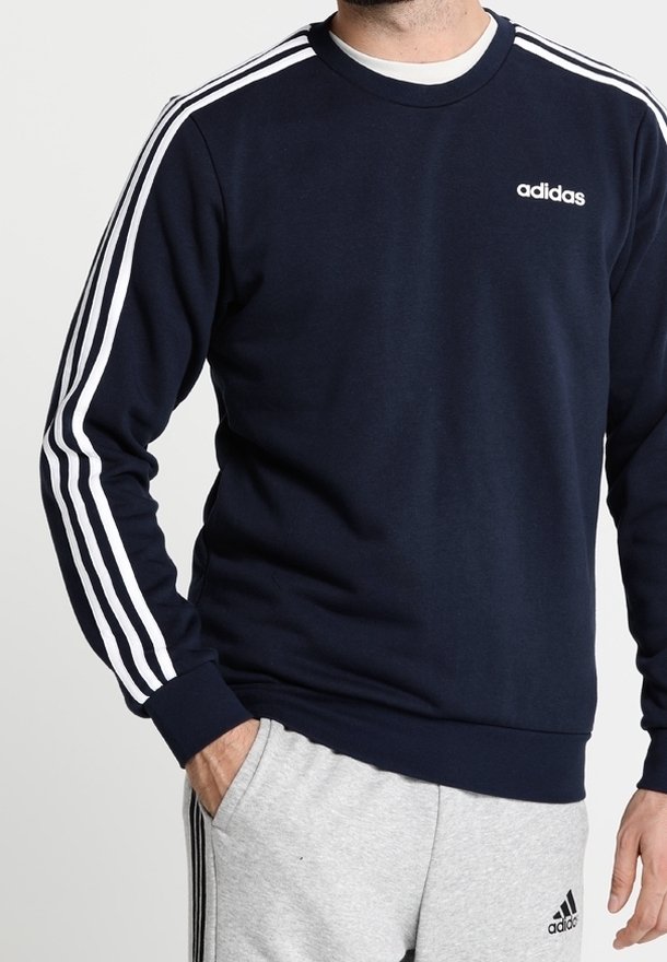 Sudadera azul marino con diseño de tres franjas blancas en las mangas y pequeño logo blanco en el pecho. Puños y bajo de canalé. Fabricada con material suave.