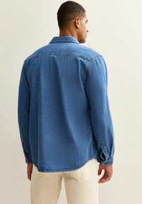 Denim overhemd in medium blauw met een kraag en lange mouwen. Heeft een ontspannen pasvorm en knoopmanchetten. Zachte textuur, casual ontwerp.