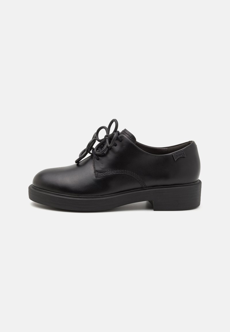 Schwarze Leder Schuhe mit einer glatten Oberfläche, ausgestattet mit markanten Schnürschlaufen und einem niedrigen, stabilen Absatz. Einfaches Design ohne zusätzliche Akzente.