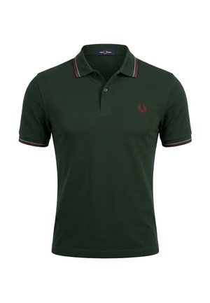 Camisa polo de manga corta en verde oscuro con cuello abotonado, ribete con rayas rojas y grises, y pequeño logo bordado en rojo en el pecho.