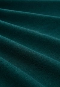 Turquoise stof met een zachte, gestructureerde oppervlakte, die een gerimpeld effect en een consistent weefpatroon over het materiaal vertoont.