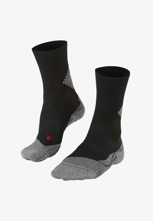 Chaussettes noires avec une texture côtelée, orteil et talon renforcés en gris, et présentant des accents géométriques blancs ainsi qu'un logo rouge au niveau de la cheville.