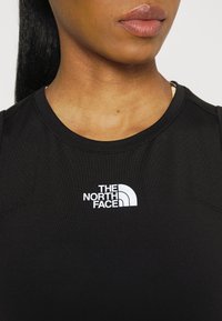 Black sleeveless athletic shirt made of smooth fabric, featuring a white logo of "The North Face" on the chest area.
