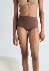 Chiloți înalți maro, confecționați dintr-un material neted, având un design fără cusături și un elastic la talie cu un logo subtil al brandului.