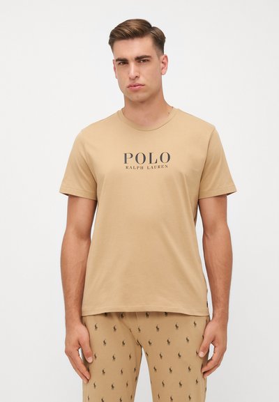 T-shirt di cotone color sabbia con scollo a girocollo e stampa frontale che recita "POLO RALPH LAUREN" in nero. Design semplice, maniche corte.