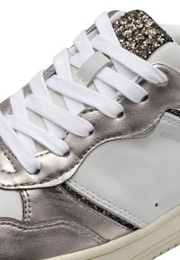 Vita sneaker med metalliska silverdetaljer och en glittrande detalj på hälen, med vita snören och en texturerad läderfinish.