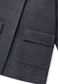 Giacca di lana grigia scura con una consistenza morbida, dotata di due tasche applicate frontali e di un colletto a revers. Design semplice, senza chiusure visibili.