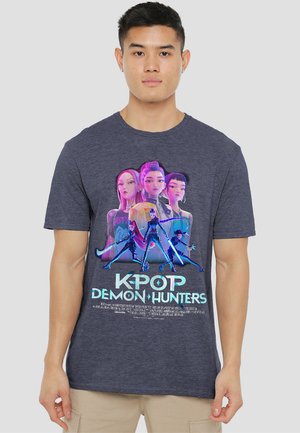 Young man wearing a dark gray T-shirt with colorful animated female characters and "K-Pop Demon Hunters" text in blue and white.