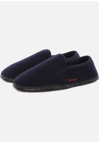Un paio di pantofole in lana blu scuro, con suole in gomma nera e un piccolo etichetta rossa "Giesswein" sul lato.