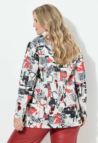 Kurtka w wielobarwny wzór z czerwieniami, czerniami i bielami, z graficznymi motywami, takimi jak serca i okulary. Długie rękawy, luźny krój.
