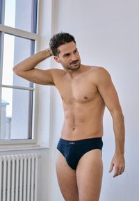 Slip da uomo blu navy con bordi rossi, realizzati in tessuto morbido. Presentano un logo sull'elastico e una vestibilità aderente per il massimo comfort.