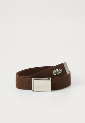 Brown elastic belt with a metal silver-colored buckle, featuring a small green embroidered crocodile logo on the strap.
