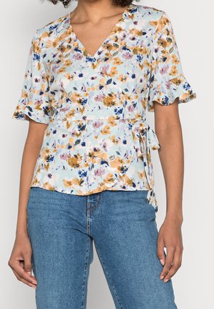Blomsterindpakket bluse i lyseblå med gule, pink og marineblå blomster. Har korte flæseærmer og en bindingdetalje i taljen.