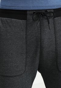 Svarta heatherade joggers med resårmidja och justerbar dragsko, med sidofickor och en mjuk, texturerad yta.